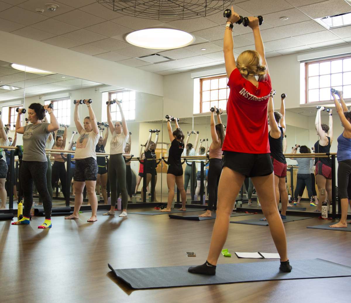 Group of people in a fitness class lifting weights.