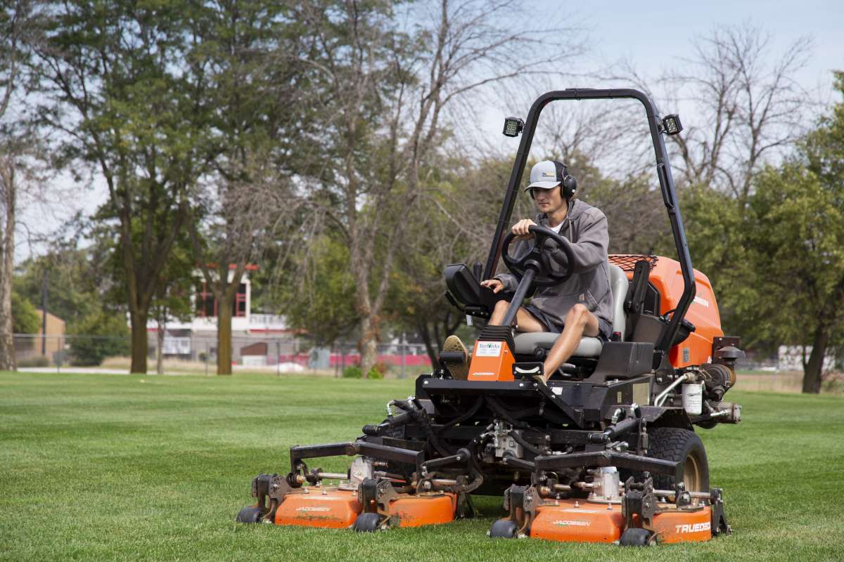 Male student mowing area of grass.