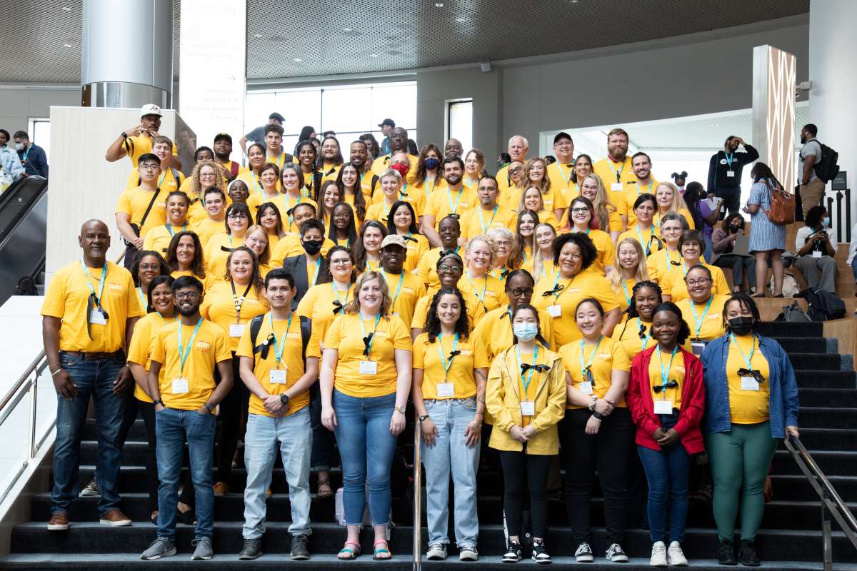 A group of students posing with matching yellow shirts